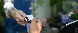 Blumenhändler nimmt Kreditkarte in Empfang. Mastercard und Visa haben sich innerhalb weniger Jahre bemerkenswert tief in den deutschen Markt für Debitkarten hineingefressen.
