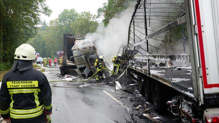 Feuerwehrleute löschen nach dem Frontalzusammenstoß zweier Lkw auf der B259 bei Büchel die Brandreste.