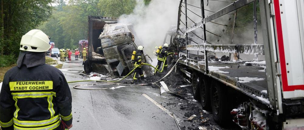 Feuerwehrleute löschen nach dem Frontalzusammenstoß zweier Lkw auf der B259 bei Büchel die Brandreste.