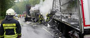 Feuerwehrleute löschen nach dem Frontalzusammenstoß zweier Lkw auf der B259 bei Büchel die Brandreste.