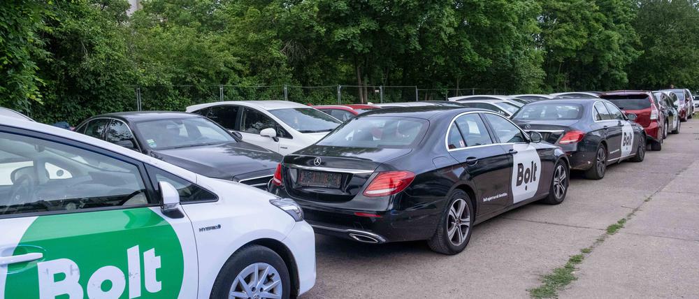 Fahrzeuge verschiedener Fahrdienstleister, wie Uber oder Bolt, stehen ohne Kennzeichen auf einer als Parkplatz genutzten Freifläche.
