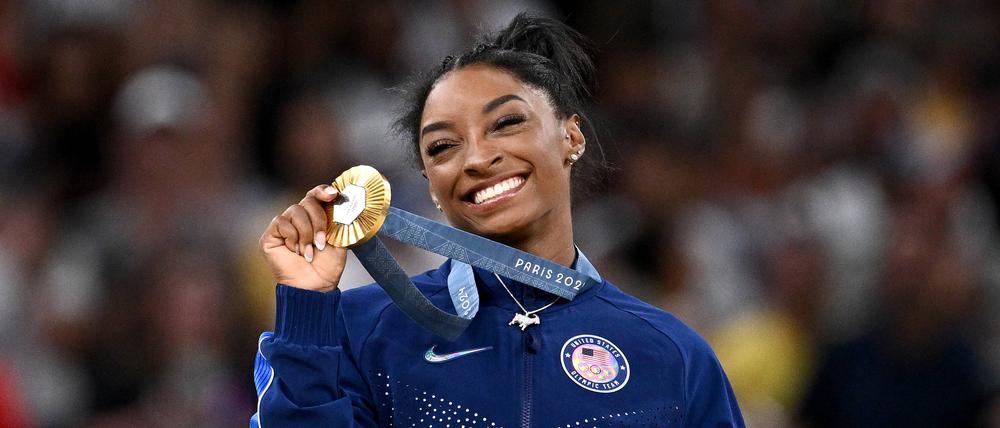 Simone Biles strahlt mir der Gold-Medaille in der Hand.