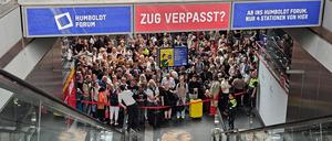 Ein Bahnmitarbeiter verkündet mit einem Megafon, welche Reisenden den Bahnsteig betreten dürfen. 