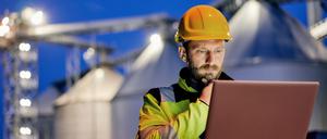 Ein Mann arbeitet am Laptop auf einer Baustelle