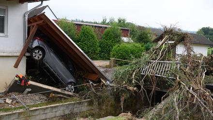 02.08.2024, Hessen, Trendelburg: Ein zerstörtes Auto liegt unter einem abgerissenen Dach nach einem Unwetter im Stadtteil Gottsbüren.