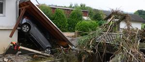 02.08.2024, Hessen, Trendelburg: Ein zerstörtes Auto liegt unter einem abgerissenen Dach nach einem Unwetter im Stadtteil Gottsbüren.