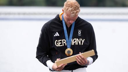 Auch der deutsche Goldmedaillengewinner Oliver Zeidler begutachtet den länglichen Gegenstand neugierig.