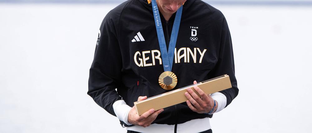 Auch der deutsche Goldmedaillengewinner Oliver Zeidler begutachtet den länglichen Gegenstand neugierig.