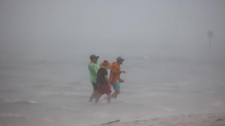 Die Freunde Forest Maddy, Yhali Ilan und Adam wagen sich in die seichten Gewässer vor dem Dunedin Causeway, während eine Sturmböe die Gegend mit Wind und Regen überschwemmt. 