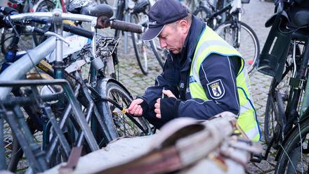 Ein Mitarbeiter vom Ordnungsamt Berlin-Mitte befestigt einen gelben Zettel an einem mutmaßlich herrenlosen Fahrrad. 