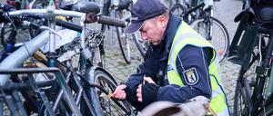 Ein Mitarbeiter vom Ordnungsamt Berlin-Mitte befestigt einen gelben Zettel an einem mutmaßlich herrenlosen Fahrrad. 