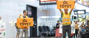 Aktivisten der „Letzten Generation“ halten Plakate während einer Störaktion am Flughafen in Österreich, Wien.