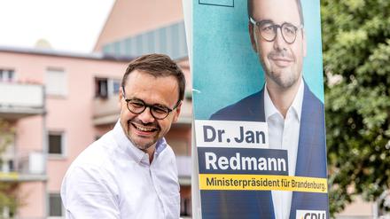 Jan Redmann, Landesvorsitzender der CDU Brandenburg, hängt ein Wahlplakat für die Landtagswahl auf.