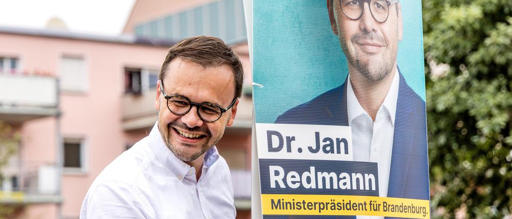 Jan Redmann, Landesvorsitzender der CDU Brandenburg, hängt ein Wahlplakat für die Landtagswahl auf.