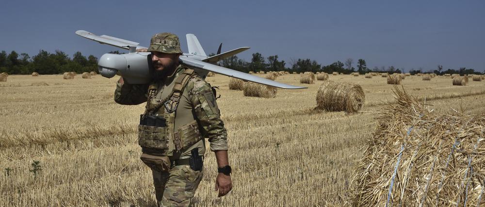 Ein Soldat der 15. Brigade der ukrainischen Nationalgarde trägt eine Aufklärungsdrohne vom Typ Leleka-100 auf einem Weizenfeld, um russische Stellungen in der Nähe der Frontlinie zu sichten.