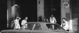Fünf Menschen stehen hinter einem Auto und blicken von der anderen Straßenseite in die Kamera im Juni 1975, in der Oudenarder Straße im Wedding. 