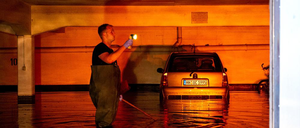 Ein Auto steht im Stadtteil Billstedt in Hamburg in einer durch Starkregen überfluteten Tiefgarage und wird vom Licht einer Warnblinkanlage angeleuchtet.