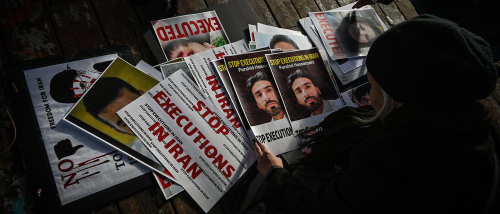 Plakate mit exekutiertem Menschen liegen auf einem Tisch als Zeichen des Protests gegen das iranische Regime.