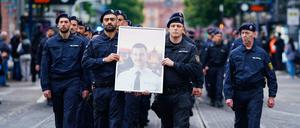 Polizisten tragen bei einem Trauermarsch für den bei einer Messerattacke tödlich verletzten Polizisten Rouven Laur dessen Bild.  