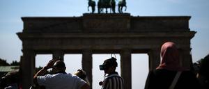 Touristen stehen mit VR-Brillen einer Stadtführung vor dem Brandenburger Tor. 