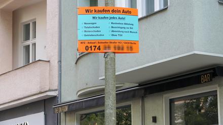 Mit illegalen Plakaten an Berliner Laternen werben Autohändler für den Ankauf von Fahrzeugen.