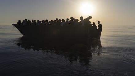 Migranten sitzen in einem Holzboot, während sie von Freiwilligen des Rettungsschiffs Ocean Viking gerettet werden (Symbolbild).