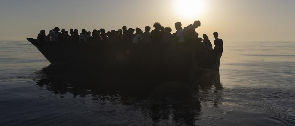 Migranten sitzen in einem Holzboot, während sie von Freiwilligen des Rettungsschiffs Ocean Viking gerettet werden (Symbolbild).