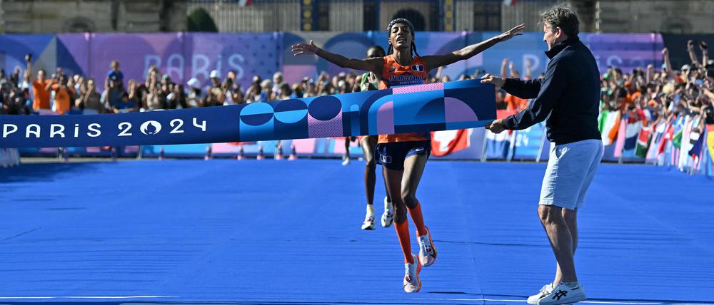 TOPSHOT - Netherlands' gold medallist Sifan Hassan crosses the finish in first place followed by Ethiopia's silver medallist Tigst Assefa in the women's marathon of the athletics event at the Paris 2024 Olympic Games at The Invalides in Paris on August 11, 2024. (Photo by Andrej ISAKOVIC / AFP)