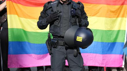 Ein Polizist steht vor einer Regenbogenfahne während eines Umzuges zum Christopher-Street-Day. (Archivbild)