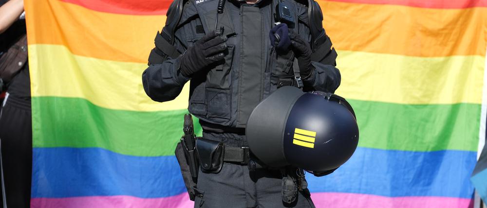 Ein Polizist steht vor einer Regenbogenfahne während eines Umzuges zum Christopher-Street-Day (CSD)