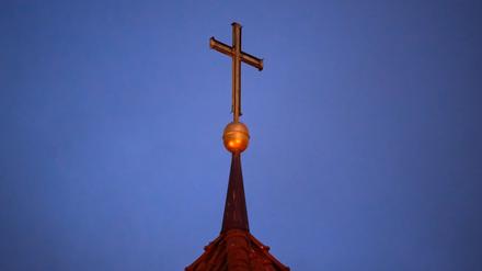 Ein Kreuz steht auf der Kirchturmspitze einer evangelischen Kirche in der Region Hannover.