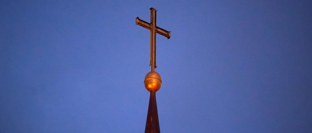 Ein Kreuz steht auf der Kirchturmspitze.