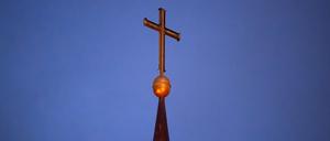 Ein Kreuz steht auf der Kirchturmspitze einer evangelischen Kirche in der Region Hannover.