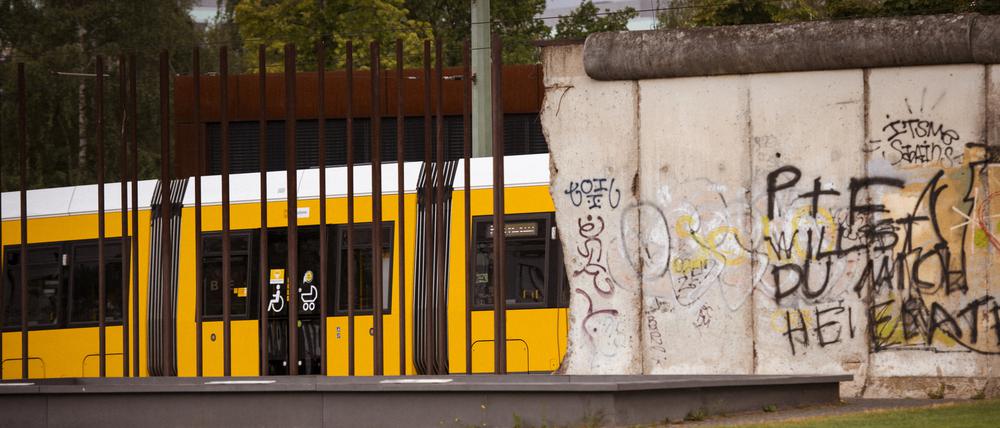Eine Straßenbahn fährt an der ehemaligen Berliner Mauer auf dem Gelände der Gedenkstätte Berliner Mauer an der Bernauer Straße vorbei.