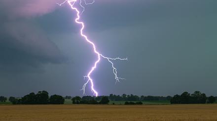Ein Blitz leuchtet in Hessen bei einem Unwetter über der Landschaft auf.
