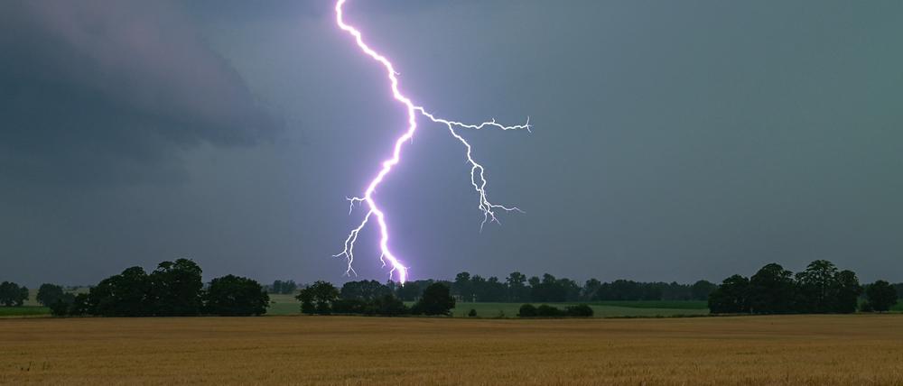 Ein Blitz leuchtet in Hessen bei einem Unwetter über der Landschaft auf. 