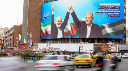 Hamas-Chef Ismail Hanija (links auf dem Bild) und Irans Präsident Massud Peseschkian auf einer Leinwand in Teheran.