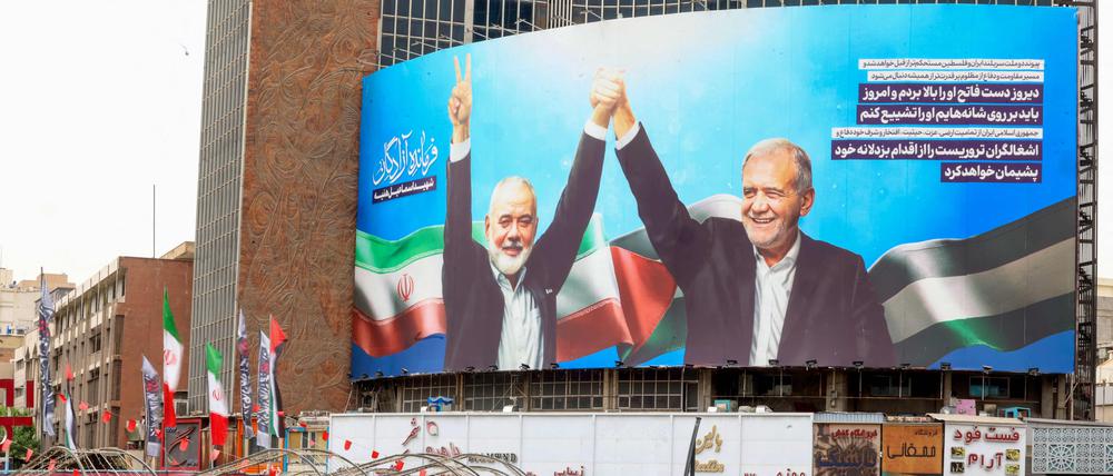 Hamas-Chef Ismail Hanija (links auf dem Bild) und Irans Präsident Massud Peseschkian auf einer Leinwand in Teheran.