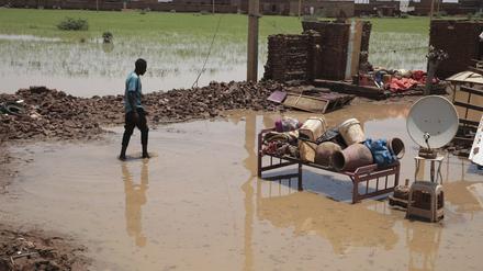 Eine Person watet nach schweren Regenfällen durch Hochwasser in der Nähe der Überreste seines Hauses im Sudan. Die Machtkämpfe und Naturereignisse haben katastrophale Folgen für die sudanesische Bevölkerung,