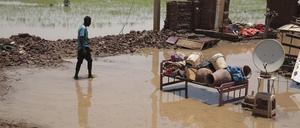 Eine Person watet nach schweren Regenfällen durch Hochwasser in der Nähe der Überreste seines Hauses im Sudan. Die Machtkämpfe und Naturereignisse haben katastrophale Folgen für die sudanesische Bevölkerung,