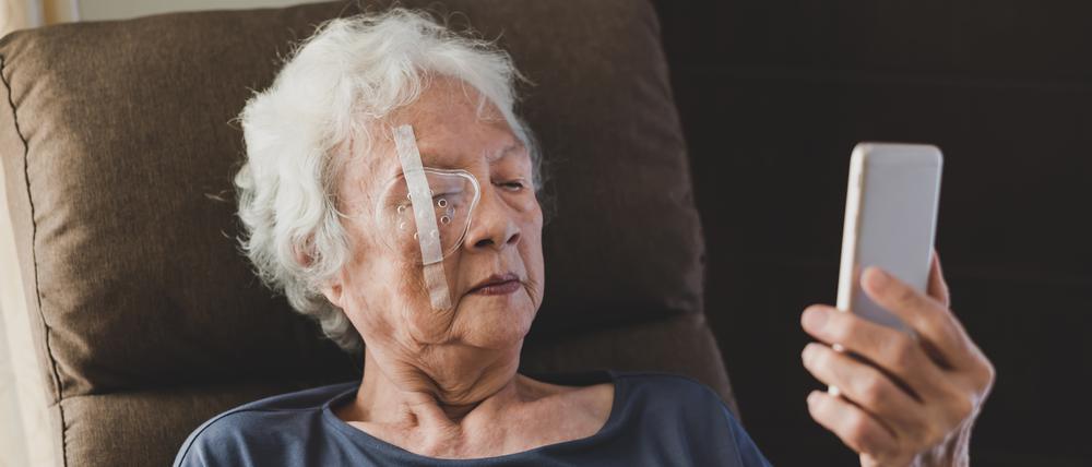 Eine ältere Dame sitzt nach einer Katarakt-OP mit einem Augenschutz in einem Sessel.