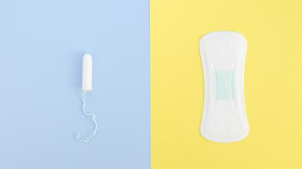 Ein Tampon und eine Slipeinlage auf blauem und gelbem Untergrund.