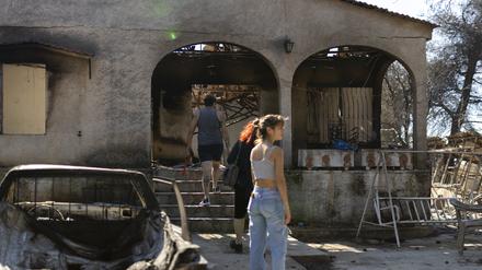 Menschen betreten ihr abgebranntes Haus nach einem Waldbrand in Ano Patima bei Penteli in der Region Nord-Athen.