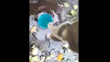 Russische Soldaten trinken aus einer Pfütze.