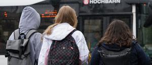 Zwei Schülerinnen und ein Schüler warten in Hamburg auf einen Bus. (Symbolbild)