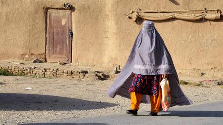 Eine in eine Burka gekleidete afghanische Frau geht eine Straße entlang.