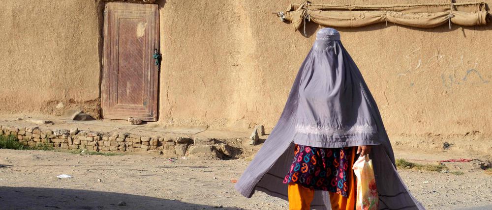 Eine in eine Burka gekleidete afghanische Frau geht eine Straße entlang.