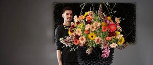  Zu sehen ist Florist Lukas Ernle vor einem großen Blumenstrauß.