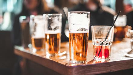 Ein halb volles Bierglas steht neben anderen Getränken.