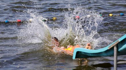 Wasser spritzt als ein Badegast im Strandbad in die Havel springt.